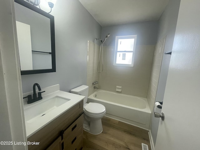 full bath with shower / tub combination, toilet, wood finished floors, visible vents, and vanity