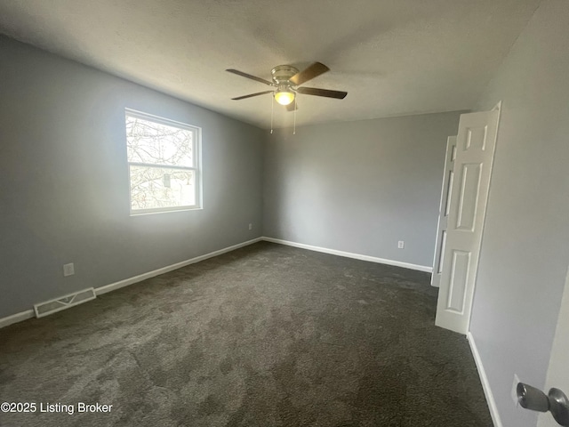 unfurnished room featuring baseboards, visible vents, dark carpet, and a ceiling fan