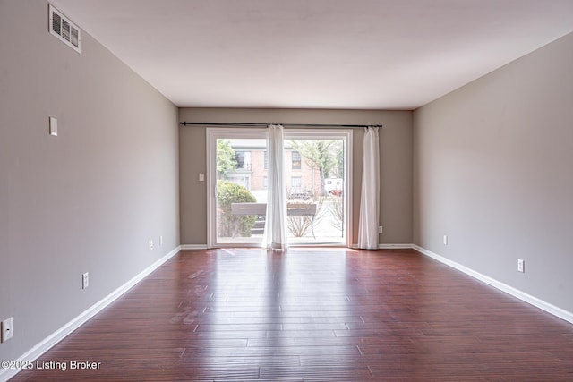 unfurnished room with baseboards, visible vents, and dark wood-style flooring