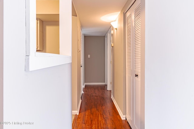 corridor with baseboards and wood finished floors