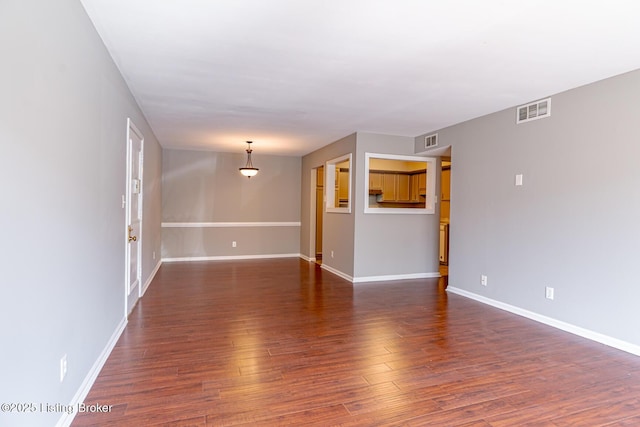 unfurnished living room with dark wood-style floors, visible vents, and baseboards