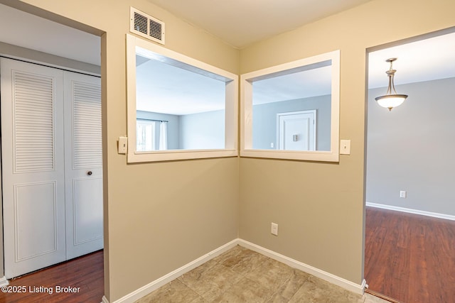 corridor featuring visible vents, baseboards, and wood finished floors