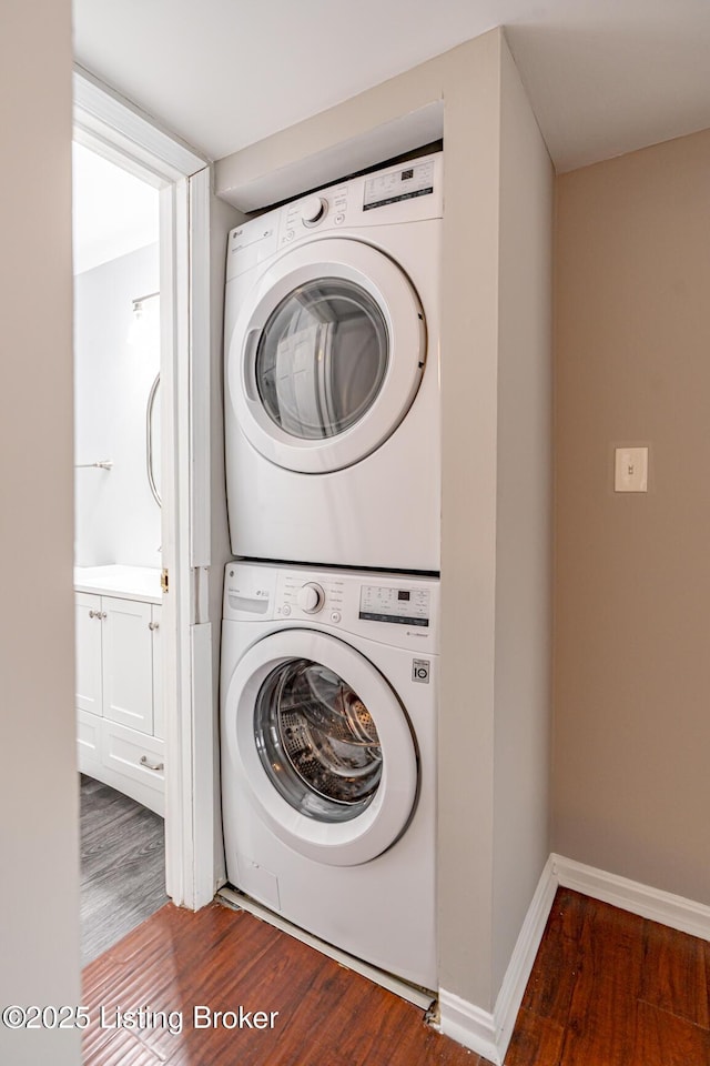 laundry room with stacked washer and clothes dryer, baseboards, dark wood-style flooring, and laundry area