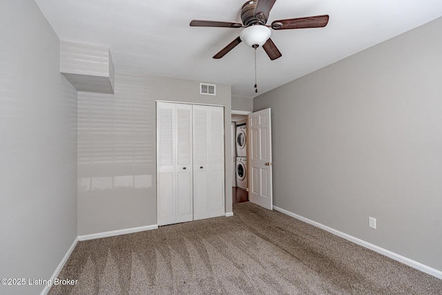 unfurnished bedroom with stacked washer and dryer, a closet, visible vents, carpet flooring, and baseboards