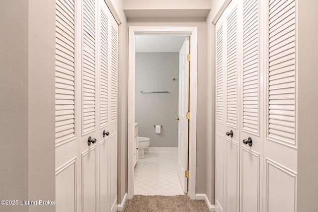 corridor with carpet, tile patterned flooring, and baseboards