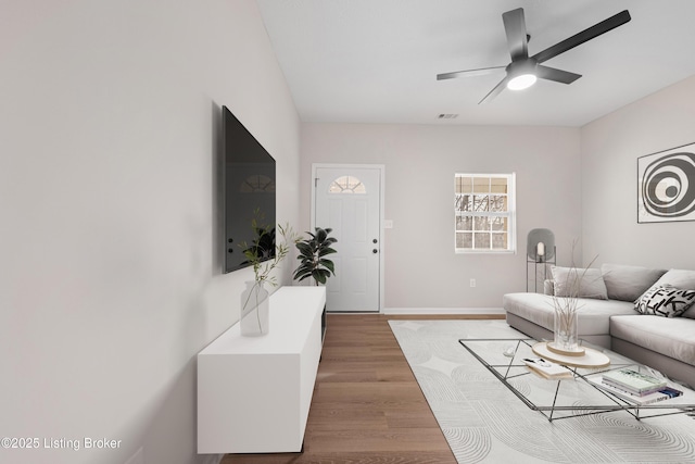 living area with light wood-style floors, visible vents, ceiling fan, and baseboards