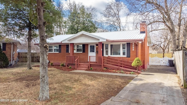 view of front facade with a chimney, metal roof, fence, cooling unit, and brick siding