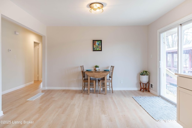 dining space featuring light wood-type flooring and baseboards