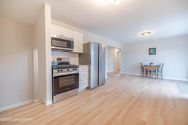 kitchen featuring stainless steel appliances, light wood finished floors, backsplash, and white cabinetry