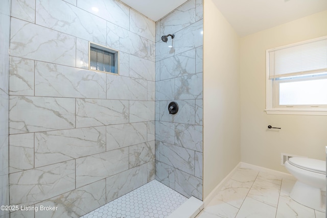 bathroom featuring marble finish floor, a tile shower, toilet, and baseboards