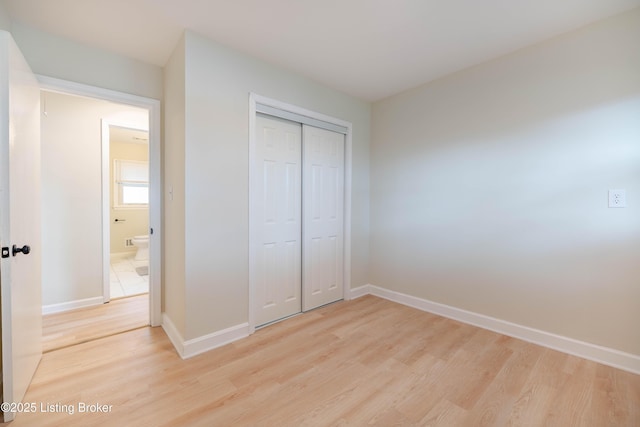 unfurnished bedroom with light wood finished floors, a closet, and baseboards