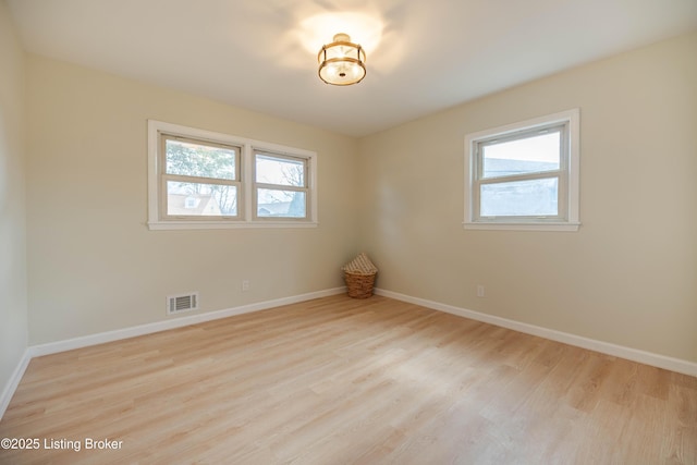 spare room featuring plenty of natural light, visible vents, and wood finished floors