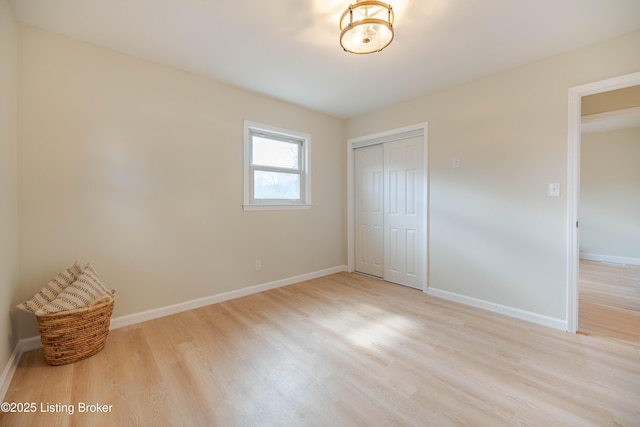 unfurnished bedroom with light wood-style floors, baseboards, and a closet