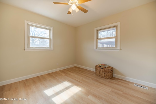 unfurnished room featuring baseboards, wood finished floors, visible vents, and a healthy amount of sunlight