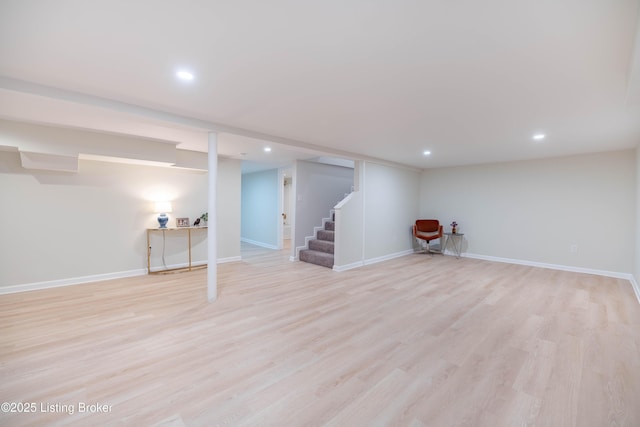 finished basement with stairs, recessed lighting, light wood-style flooring, and baseboards