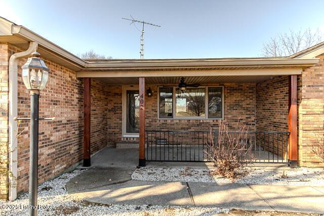 view of exterior entry with covered porch, brick siding, and a ceiling fan