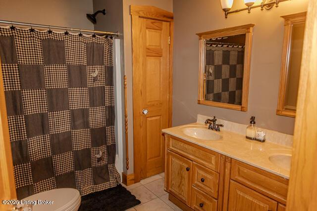 full bath featuring curtained shower, tile patterned flooring, toilet, a sink, and double vanity