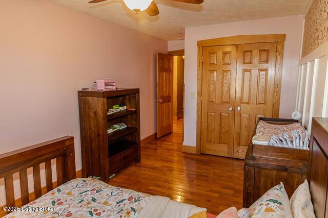 bedroom featuring a closet, wood finished floors, a ceiling fan, and baseboards