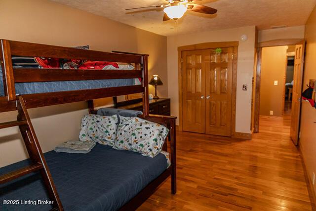 bedroom with a textured ceiling, wood finished floors, a ceiling fan, and baseboards
