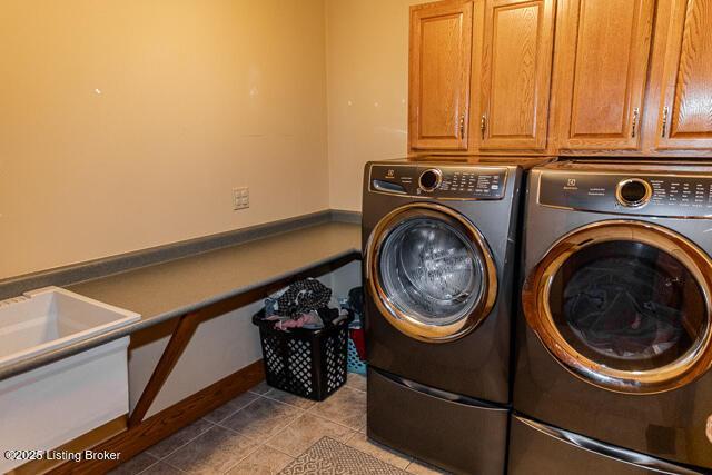 washroom with cabinet space, tile patterned flooring, and washer and dryer
