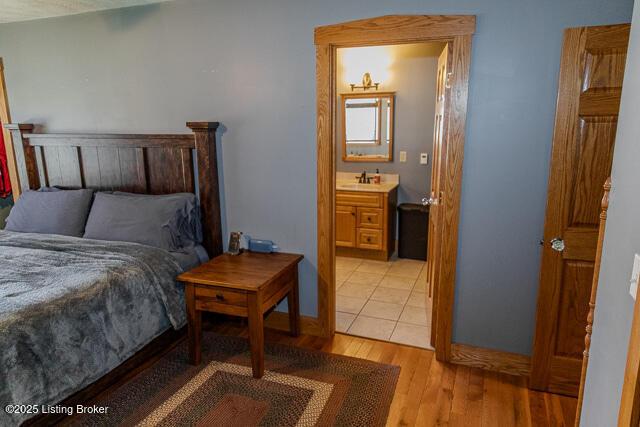 bedroom featuring ensuite bath, light wood-type flooring, and a sink