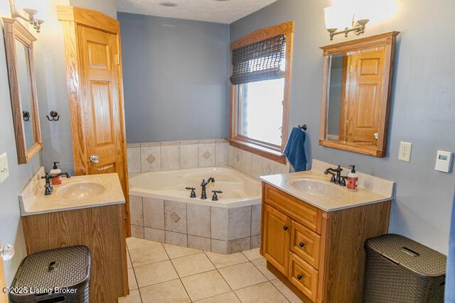 bathroom featuring two vanities, a sink, a bath, and tile patterned floors