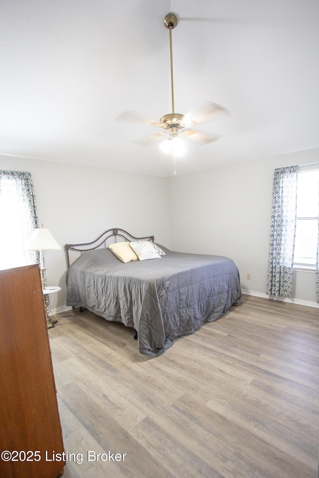 bedroom featuring a ceiling fan, baseboards, and wood finished floors