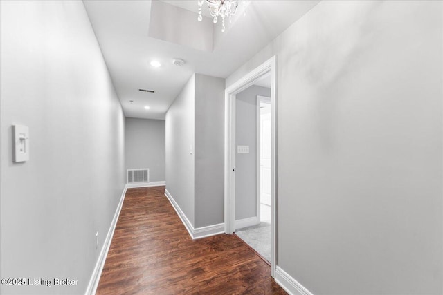 hall with visible vents, baseboards, and wood finished floors