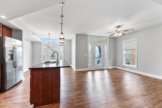 kitchen with dark wood-type flooring, a sink, dark countertops, stainless steel fridge, and a healthy amount of sunlight