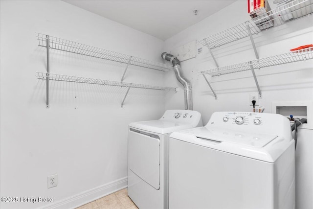 clothes washing area with baseboards, independent washer and dryer, and laundry area