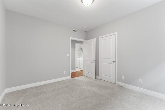 unfurnished bedroom with visible vents, washer and dryer, baseboards, and carpet