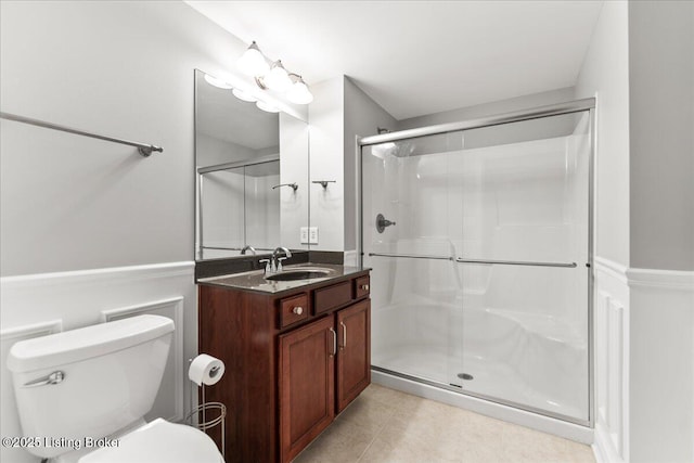 bathroom featuring vanity, toilet, a stall shower, and tile patterned flooring