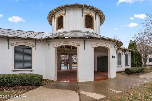 doorway to property with a standing seam roof, stucco siding, and metal roof