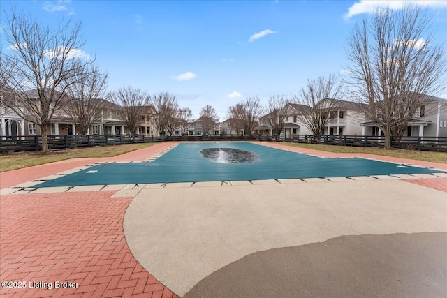 view of swimming pool featuring a patio, fence, and a residential view