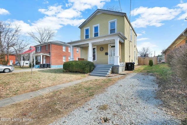 view of front of house with covered porch, driveway, and fence