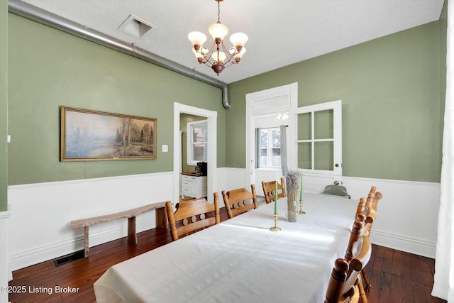 dining area featuring hardwood / wood-style floors, a notable chandelier, baseboards, and visible vents