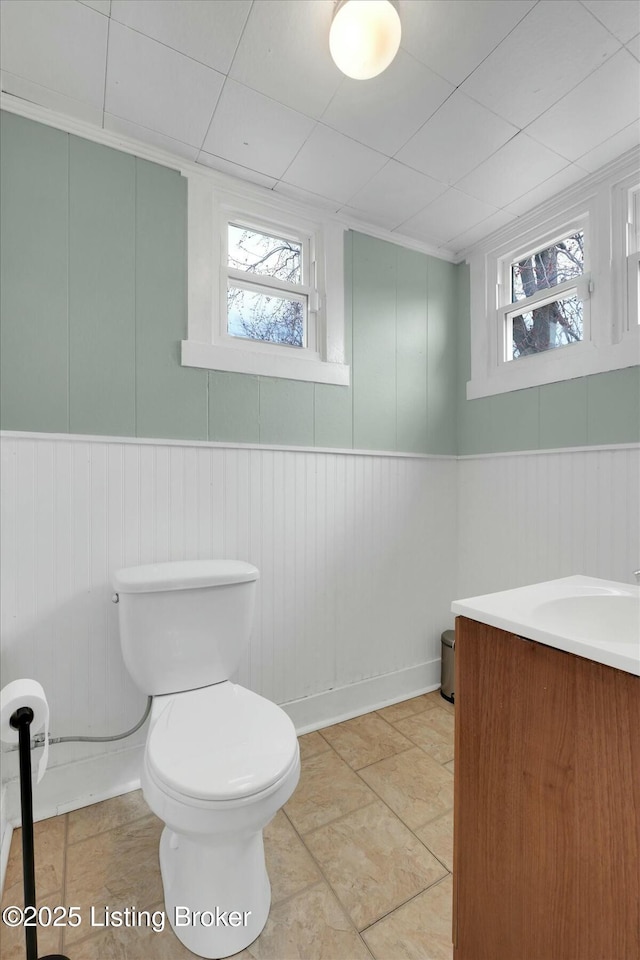 bathroom featuring a wainscoted wall, toilet, and vanity