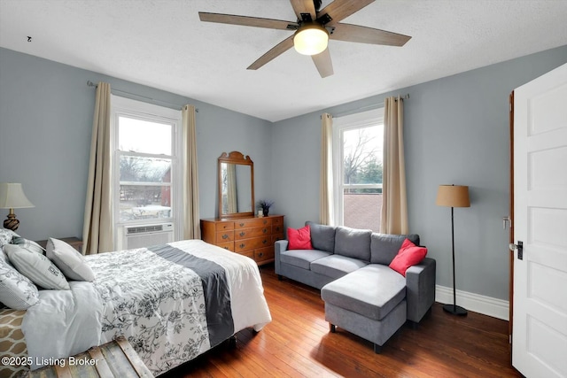 bedroom with ceiling fan, baseboards, cooling unit, wood finished floors, and a textured ceiling