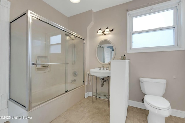 bathroom featuring toilet, baseboards, and combined bath / shower with glass door