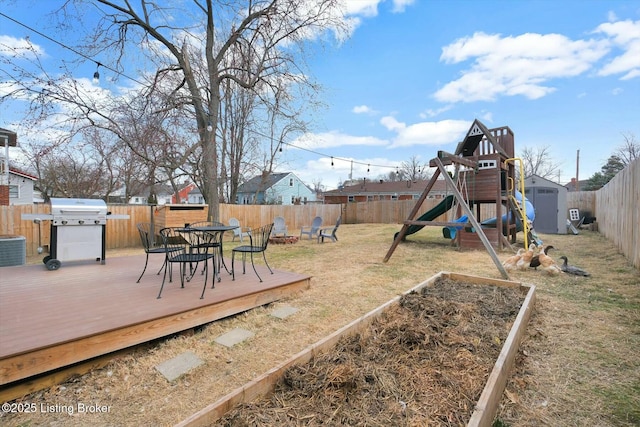 view of yard with an outdoor fire pit, a vegetable garden, a fenced backyard, a deck, and a storage shed