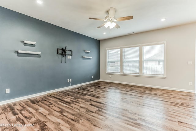 empty room featuring a ceiling fan, visible vents, baseboards, and wood finished floors