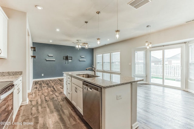 kitchen featuring visible vents, appliances with stainless steel finishes, a sink, light stone countertops, and light wood-type flooring