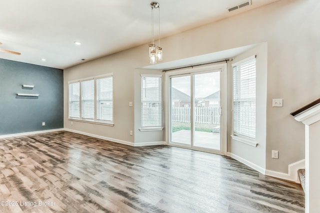 unfurnished living room featuring baseboards, plenty of natural light, visible vents, and wood finished floors