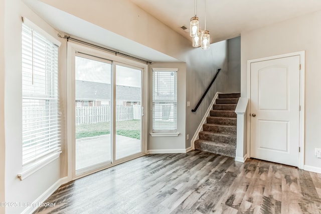 doorway featuring baseboards, stairway, wood finished floors, and a notable chandelier