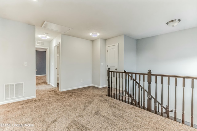 unfurnished room with carpet floors, visible vents, and baseboards