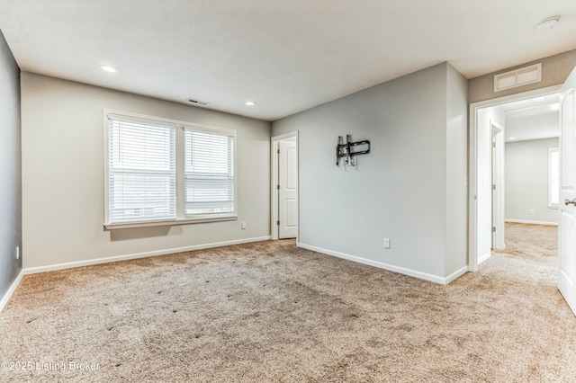 carpeted empty room with a healthy amount of sunlight, baseboards, visible vents, and recessed lighting