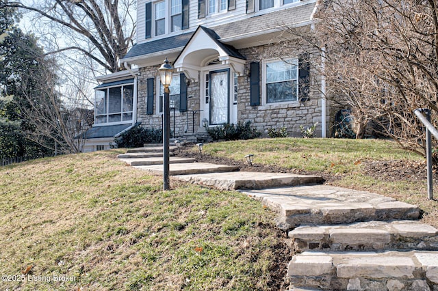 view of front of property with stone siding, a shingled roof, and a front lawn
