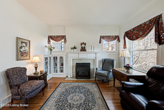 living room with a tiled fireplace, crown molding, and wood finished floors