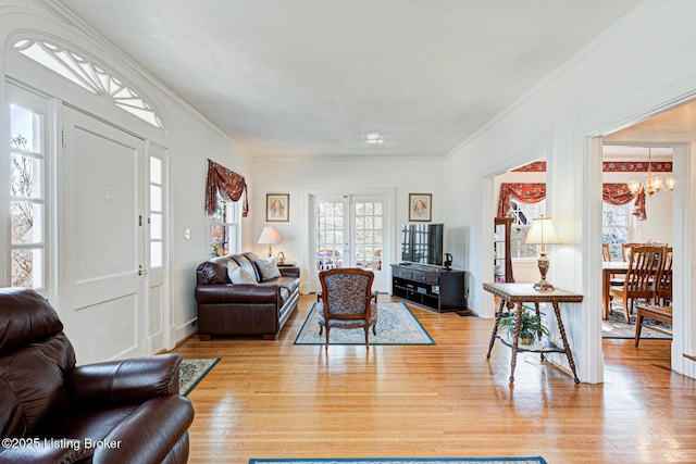 living area with an inviting chandelier, ornamental molding, and wood finished floors