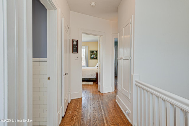 hall with wood finished floors and wainscoting